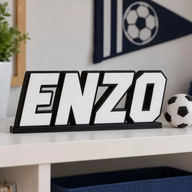 Prénom 3D Football personnalisé à poser Prénom 3D Football personnalisé à poser : lettres noires et blanches sur une étagère de chambre de garçon avec un fanion
